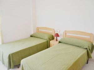 Dos camas en una habitación con sábanas verdes. en Apartment Aldea Park by Interhome, en Sant Carles de la Ràpita 8 fotos más