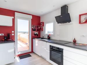 Una cocina con gabinetes blancos y una pared roja. en Apartment Les Roches Bleues-1 by Interhome, en Le Pradet