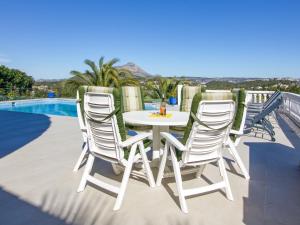 einen weißen Tisch und Stühle auf einer Terrasse mit einem Pool in der Unterkunft Villa Villa Bonheur by Interhome in Jávea