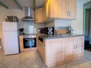 a kitchen with wooden cabinets and a sink and a refrigerator at Holiday Home Ty Coz by Interhome in Pleurtuit +10 photos