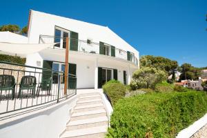 a white house with a balcony and chairs at Villa Violeta by Sonne Villas in Cala Galdana