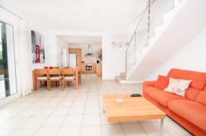 sala de estar con sofá naranja y mesa en Villa Violeta by Sonne Villas, en Cala Galdana