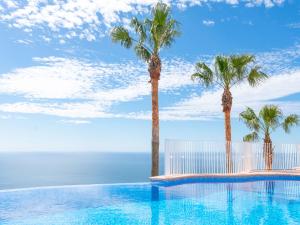 - une piscine avec des palmiers et l'océan dans l'établissement Apartment Vista Mar-1 by Interhome, à Benitachell