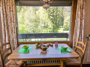 een houten tafel met een bord eten en een raam bij Apartment Alpen Roc by Interhome in Chamonix-Mont-Blanc