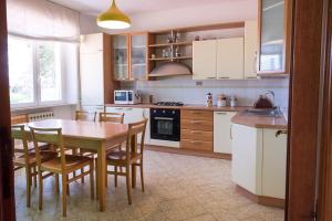 uma cozinha com mesa e cadeiras de madeira e uma cozinha com armários brancos em A11 - Varano, delizioso trilocale con giardino em Ancona