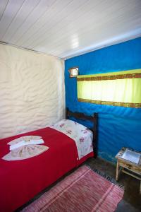 a bedroom with a red bed and a blue wall at Pousada Beija-Flor in Alto Paraíso de Goiás