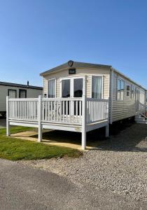 una casa móvil con porche y valla blanca en Bude holiday home, en Bude
