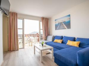 een woonkamer met een blauwe bank en een tafel bij Apartment Village Cap Estérel - Le Village-64 by Interhome in Agay - Saint Raphael