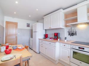 eine Küche mit weißen Schränken, einem Tisch und einem Esszimmer in der Unterkunft Apartment Le Giono by Interhome in Saint-Laurent-du-Var