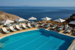 a pool with chairs and umbrellas and the ocean at Aria Boutique Hotel in Chora Folegandros