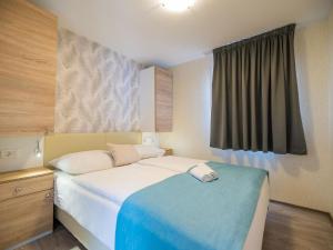 a bedroom with a white bed with a blue blanket at Holiday Home Sea View mobile home by Interhome in Šilo