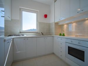 Biała kuchnia z białymi szafkami i oknem w obiekcie Apartment Martina by Interhome w mieście Vrbnik