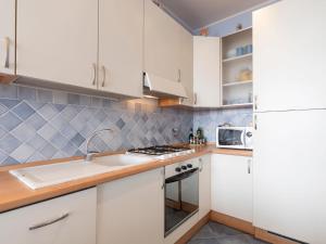 kuchnia z białymi szafkami, zlewem i lodówką w obiekcie Apartment Rocce di Capo Mimosa by Interhome w mieście Cervo