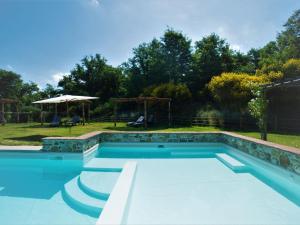 uma piscina com escadas num quintal com guarda-sol em Apartment Pino by Interhome em Osteria Delle Noci