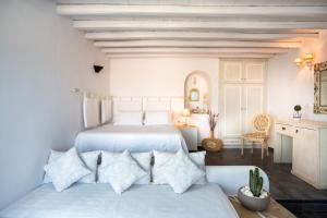 a white bedroom with two beds and a table at Aria Boutique Hotel in Chora Folegandros +64 photos
