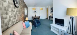 een woonkamer met een bank en een tv bij Shoreline Apartment Katwijk in Katwijk aan Zee