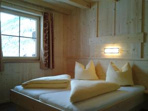 Zimmer mit einem Bett mit Kissen und einem Fenster in der Unterkunft Alois & Elisabeth, Chalet in Tux