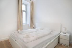 een wit bed in een witte kamer met een raam bij Cottageviertel - Stilvolles Apartment in Parknähe in Wenen