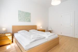 una camera da letto con un grande letto con lenzuola bianche di Cottageviertel - Stilvolles Apartment in Parknähe a Vienna
