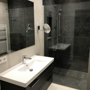 a bathroom with a sink and a shower with a mirror at Strand FeWo Rügen MoonLoft in Binz +21 photos