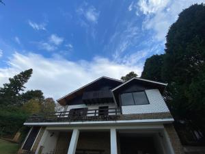 a house with a balcony on top of it at Chalé Uirapurus in Monte Verde
