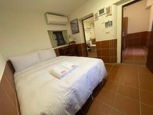 1 dormitorio con 1 cama con 2 toallas en 左營蓮潭郭家百年古厝 en Kaohsiung