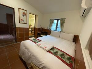 um quarto com uma cama com lençóis brancos e almofadas em 左營蓮潭郭家百年古厝 em Kaohsiung