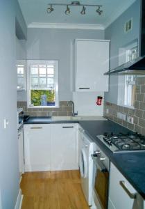 a kitchen with white cabinets and a stove top oven at Victorian Building With Character in London