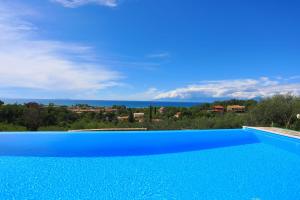 a blue swimming pool with a view of the ocean at Villa Dersea in Acharavi