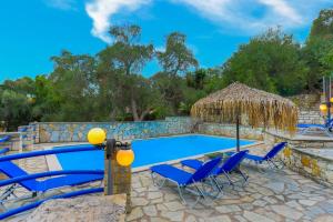een zwembad met stoelen en een tafel en een strohut bij Villa Alkinoos in Gaios