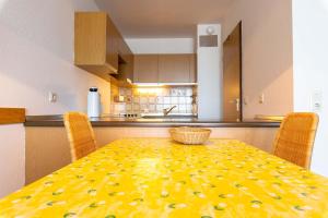 eine Küche mit einem Tisch mit einem gelben gemusterten Tischtuch in der Unterkunft Ferienwohnpark Immenstaad am Bodensee Zwei-Zimmer-Apartment 49 45 in Immenstaad am Bodensee