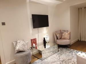 a living room with two chairs and a tv on the wall at Cozy Muswell Hill 1-Bedroom Flat in London
