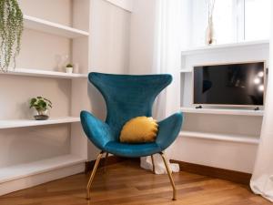 - une chaise bleue avec un oreiller jaune dans le salon dans l'établissement The Best Rent - Apartment near Piazza di Spagna, à Rome