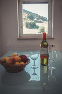 a bottle of wine and two glasses on a table with a basket of fruit at Apartma Sonček, on the ski slopes, balcony, private parking in Kranjska Gora