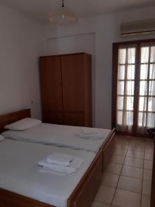 a bedroom with a bed with white sheets and a cabinet at Zaga Apartments - Flats in Koroni