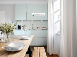 a kitchen with a wooden table and white cabinets at Numa Salzburg Flute in Salzburg