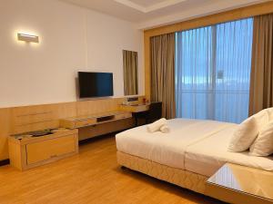 a hotel room with a bed and a flat screen tv at Imperial Grand Suite Apartment Kuching in Kuching