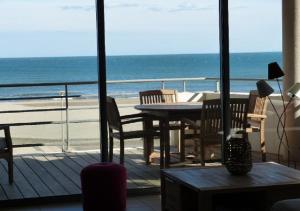 een balkon met een tafel en stoelen en het strand bij La Perle Marine, Luxe et Raffinement, appartement T4 vue mer in Narbonne