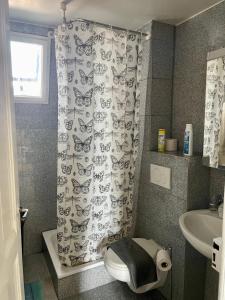 La salle de bains est pourvue de toilettes et d'un rideau de douche avec des papillons. dans l'établissement Lake view Lausanne, à Lausanne