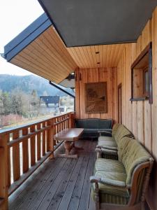 a porch with a couch and a table on a deck at Noclegi Kamionka in Cisna