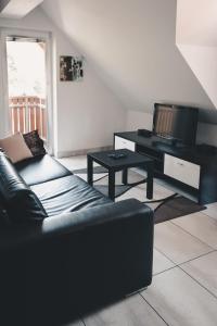 a living room with a black couch and a tv at Apartma Sonček, on the ski slopes, balcony, private parking in Kranjska Gora