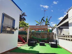 un patio trasero con alfombra verde y parque infantil en La Caseta de Jose, en Mareny Barraquetas