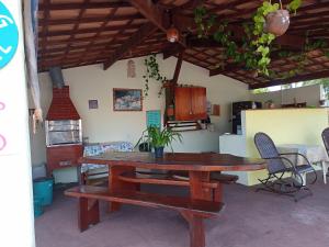 a wooden table and bench in a room with a table and chairs at Camping e Hostel Praia do Saco in Estância