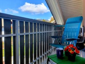 una sedia blu su una veranda con tavolo e fiori di Apartma DAVID a Zgornje Gorje