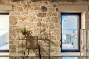 uma cadeira de vime fica em frente a uma parede de pedra em Evangelia Casa, comfy stay, centrally, with views! em Heraclião