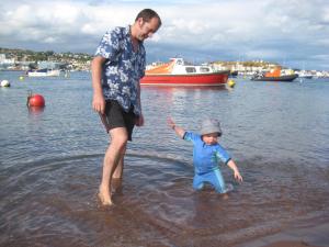 mężczyzna i dziecko stojący w wodzie w obiekcie Dolphin Cottage 50m from Shaldon Beach! w mieście Shaldon