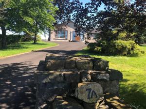 a stone wall in front of a house at Slemish View - a beautiful setting in countryside in Ballymena