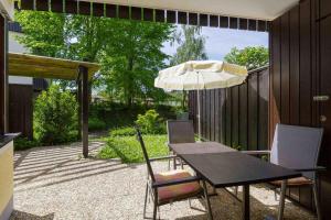 a table and chairs with an umbrella on a patio at Ferienwohnpark Immenstaad am Bodensee Ein-Zimmer-Apartment 55 03 in Immenstaad am Bodensee