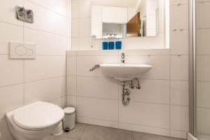 La salle de bains blanche est pourvue de toilettes et d'un lavabo. dans l'établissement Ferienwohnpark Immenstaad am Bodensee Ein-Zimmer-Apartment 55 17, à Immenstaad am Bodensee