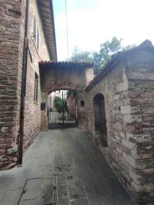 un callejón en un viejo edificio de ladrillo con una puerta en All'Archetto del Terz'Ordine en Assisi